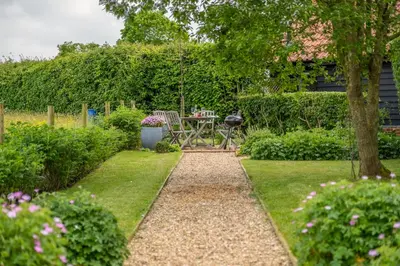 a garden with a table and chairs and a grill at Elegant luxurious cottage - The Dove House in Ipswich