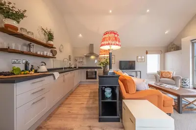 a kitchen with white cabinets and an orange couch at Elegant luxurious cottage - The Dove House in Ipswich