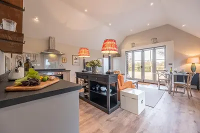 a kitchen and living room with a table and chairs at Elegant luxurious cottage - The Dove House in Ipswich
