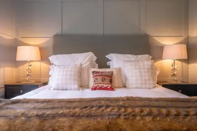 a bedroom with a bed with pillows and two lamps at Elegant luxurious cottage - The Dove House in Ipswich