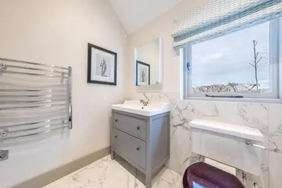 a bathroom with a sink and a toilet and a window at Elegant luxurious cottage - The Dove House in Ipswich
