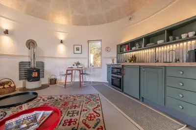 a kitchen with green cabinets and a table with a rug at Extraordinarily converted grain stores - The Silos in Ipswich