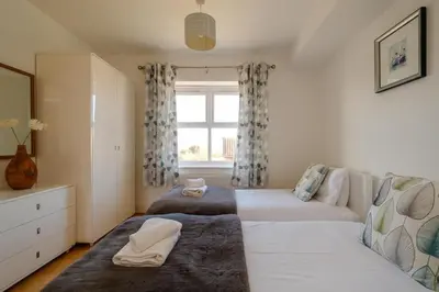 a bedroom with two beds and a window at Admiral's Rest in Aldeburgh