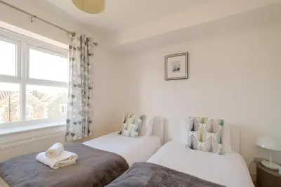 two beds in a room with a window at Admiral's Rest in Aldeburgh