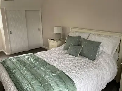 a bed with green and white sheets and pillows at Klara's House in West Mersea