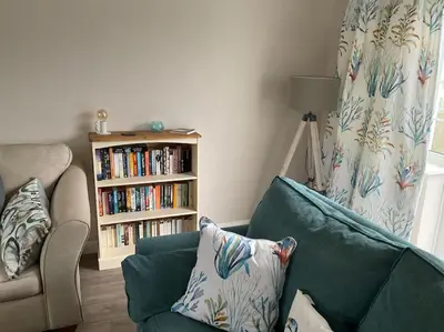 a living room with a green couch and a book shelf at Klara's House in West Mersea