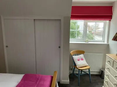 a bedroom with a bed and a chair and a window at Klara's House in West Mersea