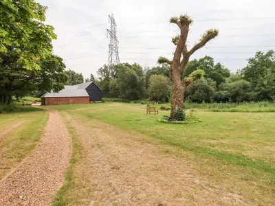 a field with a tree and a barn at The Granary in Colchester