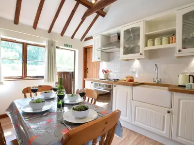 a kitchen with a table and chairs and a kitchen with white cabinets at The Stables in Colchester