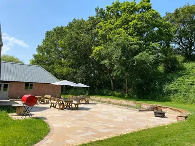 a patio with tables and picnic tables in a yard at The Stables in Colchester