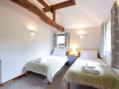 two beds in a room with white walls and windows at The Stables in Colchester