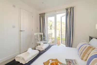 a bedroom with a bed and a window with a chair at The Garden Flat in Aldeburgh
