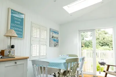 a kitchen with a table with chairs and a window at The Garden Flat in Aldeburgh