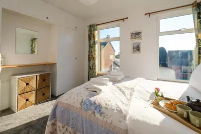 a bedroom with a bed with a tray of bread on it at 39 Carr Avenue - Aldeburgh Coastal Cottages in Leiston