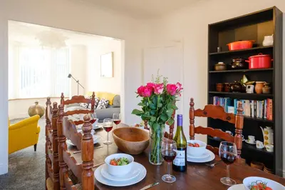 a dining room table with flowers and wine glasses at 39 Carr Avenue - Aldeburgh Coastal Cottages in Leiston