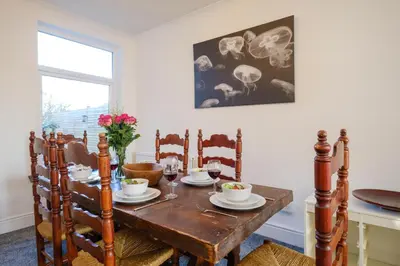 a dining room with a wooden table and chairs at 39 Carr Avenue - Aldeburgh Coastal Cottages in Leiston