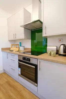 a kitchen with white cabinets and a stove top oven at 39 Carr Avenue - Aldeburgh Coastal Cottages in Leiston