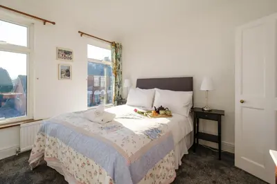a bedroom with a large bed and a window at 39 Carr Avenue - Aldeburgh Coastal Cottages in Leiston