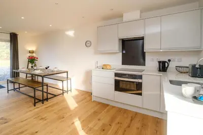 a kitchen with white cabinets and a wooden floor at Three Tuns - Garden Suite 1 in Wickham Market