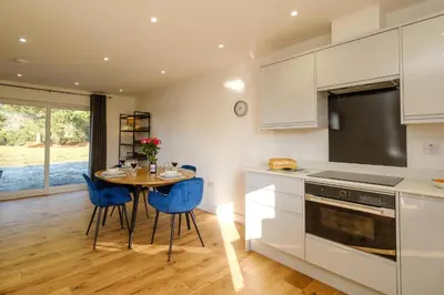 a kitchen with a table and blue chairs at Three Tuns - Garden Suite 2 in Wickham Market