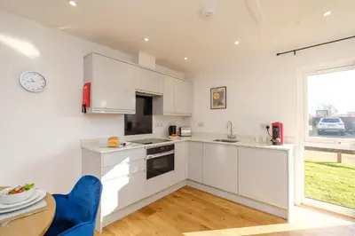 a kitchen with white cabinets and a table and a window at Three Tuns - Garden Suite 2 in Wickham Market