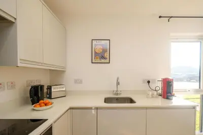 a kitchen with white cabinets and a bowl of oranges on the counter at Three Tuns - Garden Suite 2 in Wickham Market