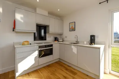 a white kitchen with white cabinets and a window at Three Tuns - Garden Suite 3 in Wickham Market