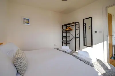 a bedroom with a white bed and a mirror at Three Tuns - Garden Suite 3 in Wickham Market