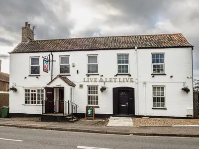 a white building on the corner of a street at The Live and Let Live in Downham Market