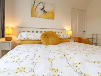 a bedroom with a white bed with yellow flowers on it at Rector's Retreat in Ipswich