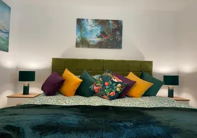 a bedroom with a bed with colorful pillows at Contemporary, Cosy & Homely 2 Bed Apartment with High-Speed WIFI, Terrace & Free Parking overlooking Stourbridge Common Park & Coldham's Brook in Cambridge