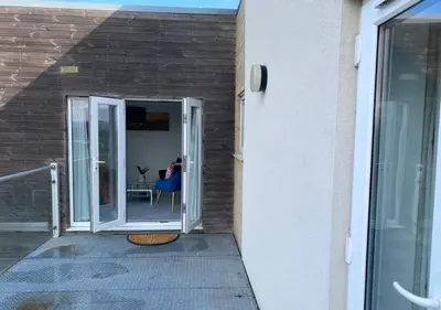 a door to a patio with a person sitting at a table at Contemporary, Cosy & Homely 2 Bed Apartment with High-Speed WIFI, Terrace & Free Parking overlooking Stourbridge Common Park & Coldham's Brook in Cambridge