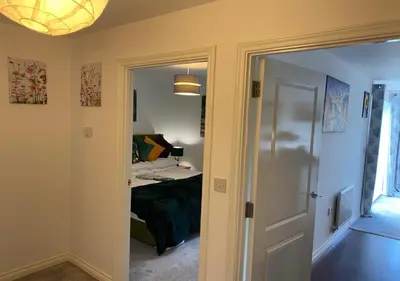 a bedroom with a bed and a door leading into a room at Contemporary, Cosy & Homely 2 Bed Apartment with High-Speed WIFI, Terrace & Free Parking overlooking Stourbridge Common Park & Coldham's Brook in Cambridge