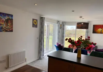 a living room with a vase of flowers on a table at Contemporary, Cosy & Homely 2 Bed Apartment with High-Speed WIFI, Terrace & Free Parking overlooking Stourbridge Common Park & Coldham's Brook in Cambridge