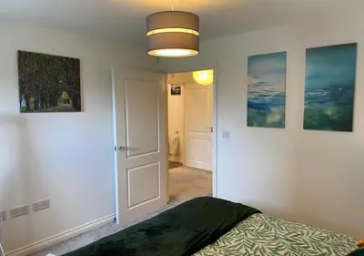 a bedroom with a bed and paintings on the walls at Contemporary, Cosy & Homely 2 Bed Apartment with High-Speed WIFI, Terrace & Free Parking overlooking Stourbridge Common Park & Coldham's Brook in Cambridge