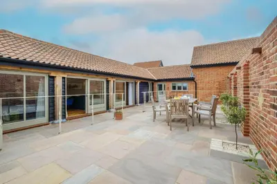 a patio with a table and chairs and a brick building at Alde Bay Farm - Oyster Catcher in Aldeburgh