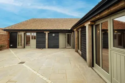 a house with a large patio in front of it at Alde Bay Farm - Coral Cottage in Aldeburgh