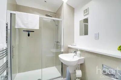 a white bathroom with a shower and a sink at Lovely 1 Bedroom Flat with Free Off Road Parking in Chesterton