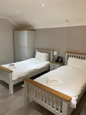 two beds in a room with white sheets and a telephone at Ye Olde Plough House in East Horndon