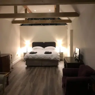 a bedroom with a bed and two lamps and a couch at The Stables in Colchester