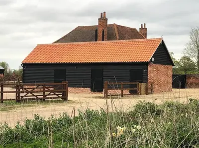 an old black barn with a red roof at The Stables in Colchester