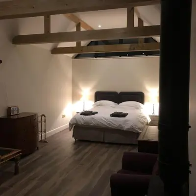 a bedroom with a bed and a wooden floor at The Stables in Colchester