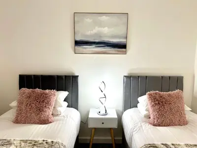 two beds with pillows and a picture on the wall at Kiwi Tree Serviced Apartment in Cambridge