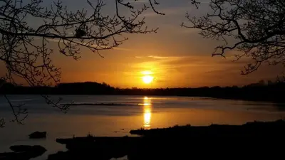 a sunset on a lake with the sun setting at River View - Stunning estuary views in Aldeburgh