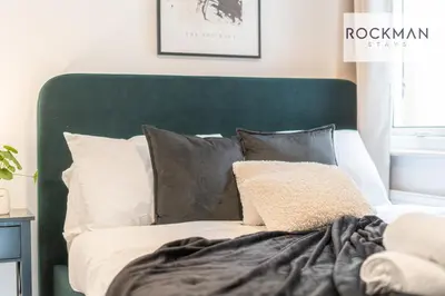 a bed with a green headboard and pillows at 5 Bed Apartment Close To Beach with Off-street parking - Perfect for Contractors - Fast Wi-Fi - Close to beach in Southend-on-Sea