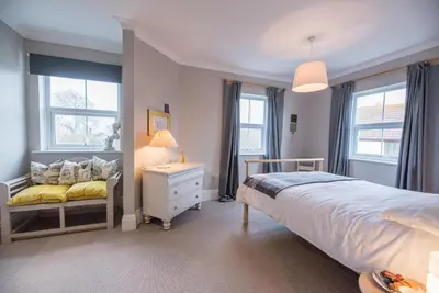a bedroom with a bed and two windows at 3 St Nicholas Court, Aldeburgh in Aldeburgh