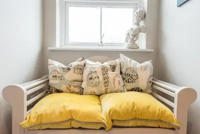 a white bench with pillows and a window at 3 St Nicholas Court, Aldeburgh in Aldeburgh