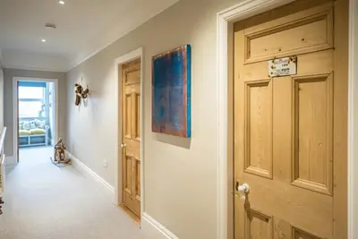 a hallway with a door and a painting on the wall at 3 St Nicholas Court, Aldeburgh in Aldeburgh