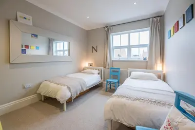 a bedroom with two beds and a mirror at 3 St Nicholas Court, Aldeburgh in Aldeburgh