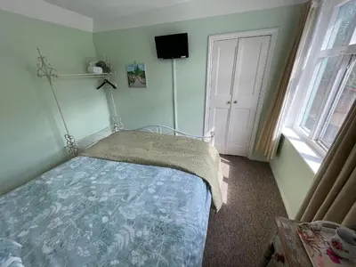 a bedroom with a bed and two windows and a door at The Bridge Street Historic Guest House in Sudbury